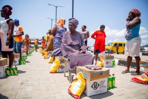 A group of women receiving aid packages from Lagos Food Bank on a sunny day.